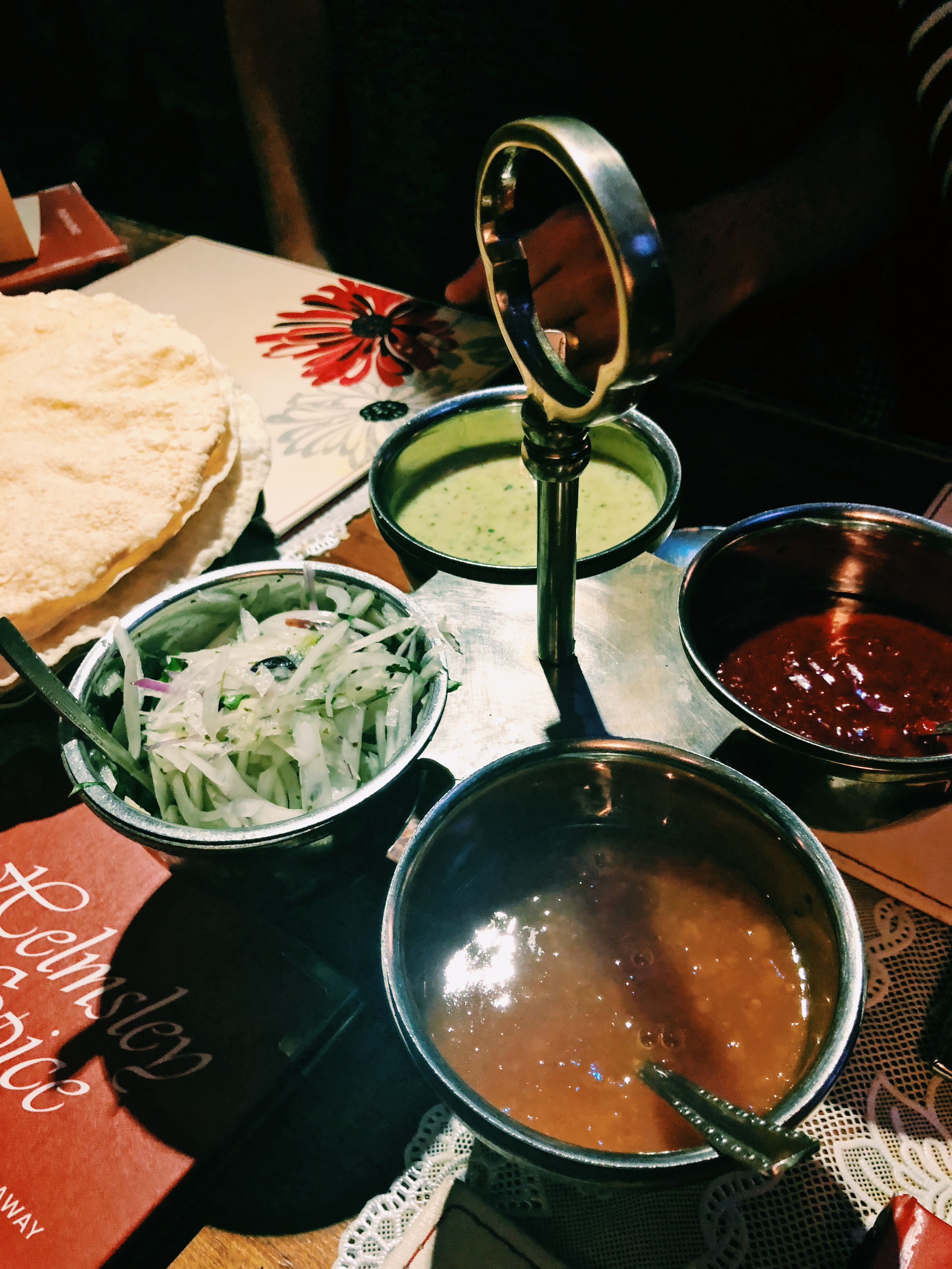 A tray of poppadoms with a variety of colourful Indian dips and mint sauce