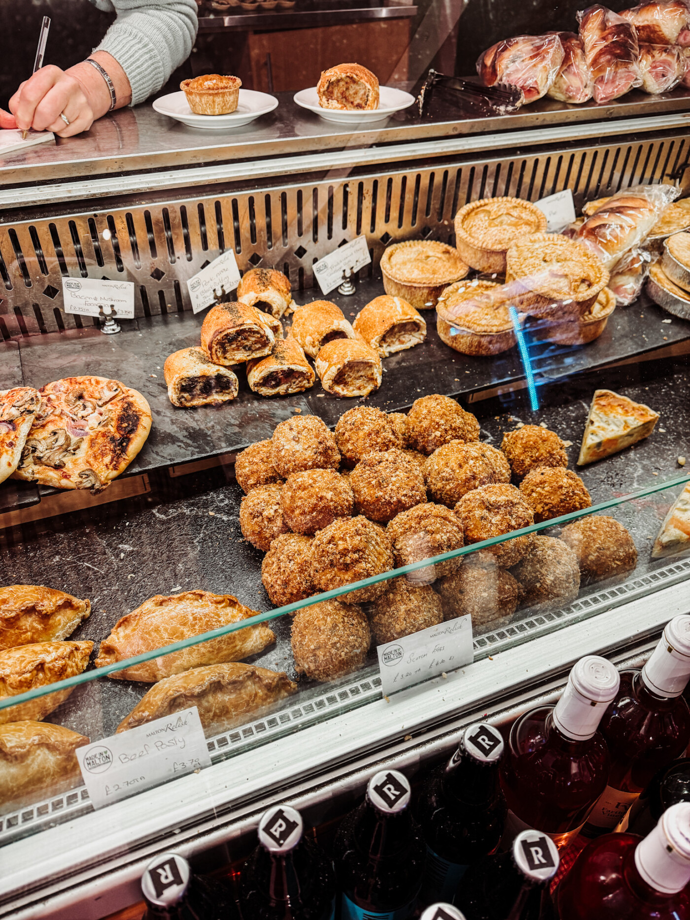 Deli counter at Malton Relish showing Yorkshire cheeses, sausage rolls and pork pies for sale